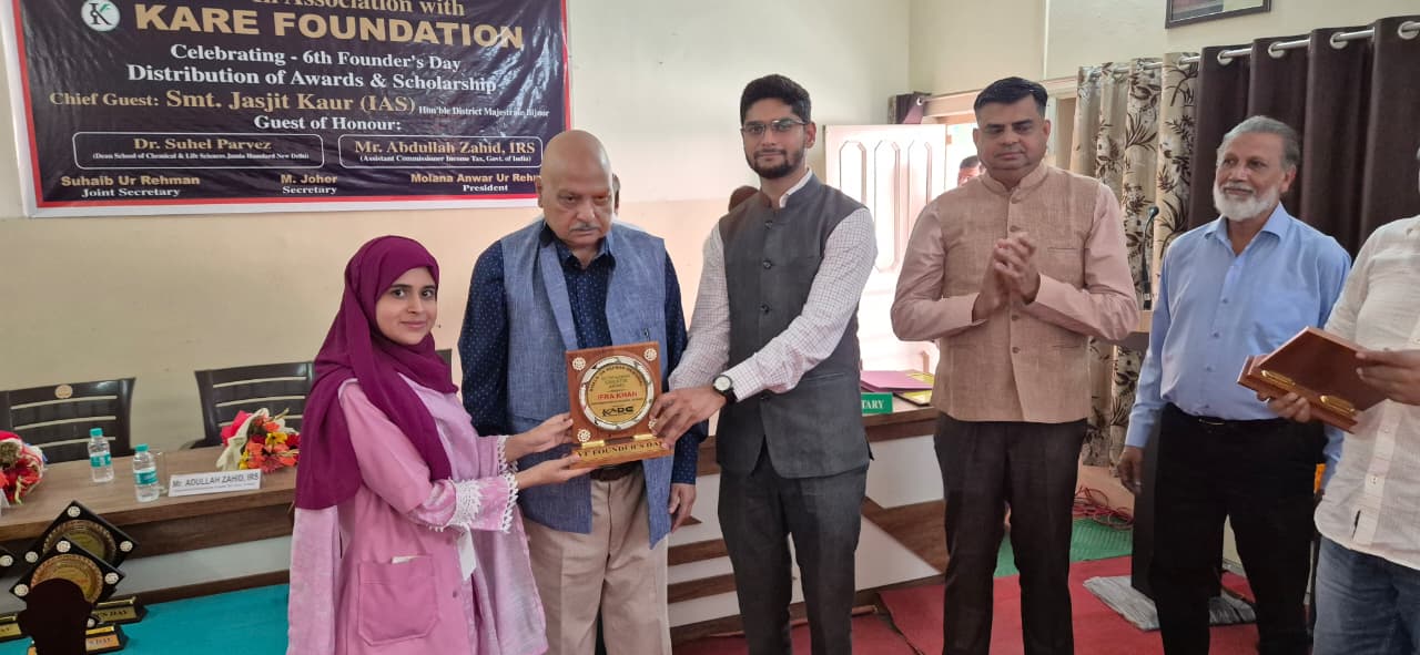 Young scholar in hijab receiving award from foundation officials - 2025